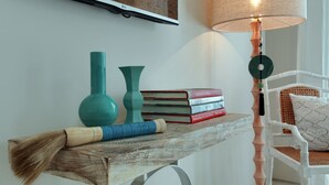 A wooden shelf with a broom, two vases, and a stack of books. - Room & Vespa 4 (Seminyak)