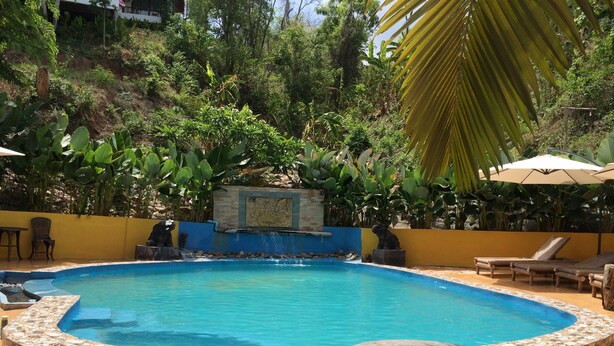 A circular pool with a stone border, surrounded by lounge chairs and a wooden table. - Chang Pai (Pai)