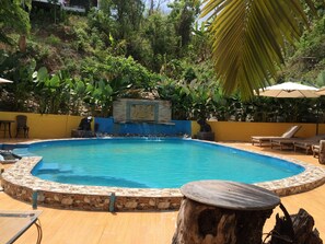 A circular pool with a stone border, surrounded by lounge chairs and a wooden table. - Chang Pai (Pai)