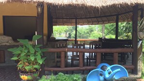 A thatched-roof outdoor seating area with a view of greenery. - Chang Pai (Pai)