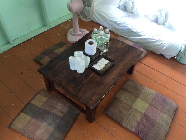 A small wooden table with a fan, bottled water, and tissues. - Chang Pai (Pai)