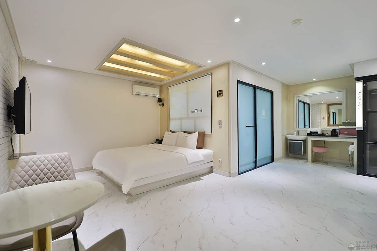 A modern hotel room with a bed, bedside table, and a small seating area.