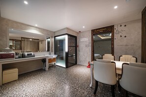 A modern hotel room with a large mirror, a glass-enclosed shower, a dining area with chairs, and a minibar. - Time Hotel (Yangsan)
