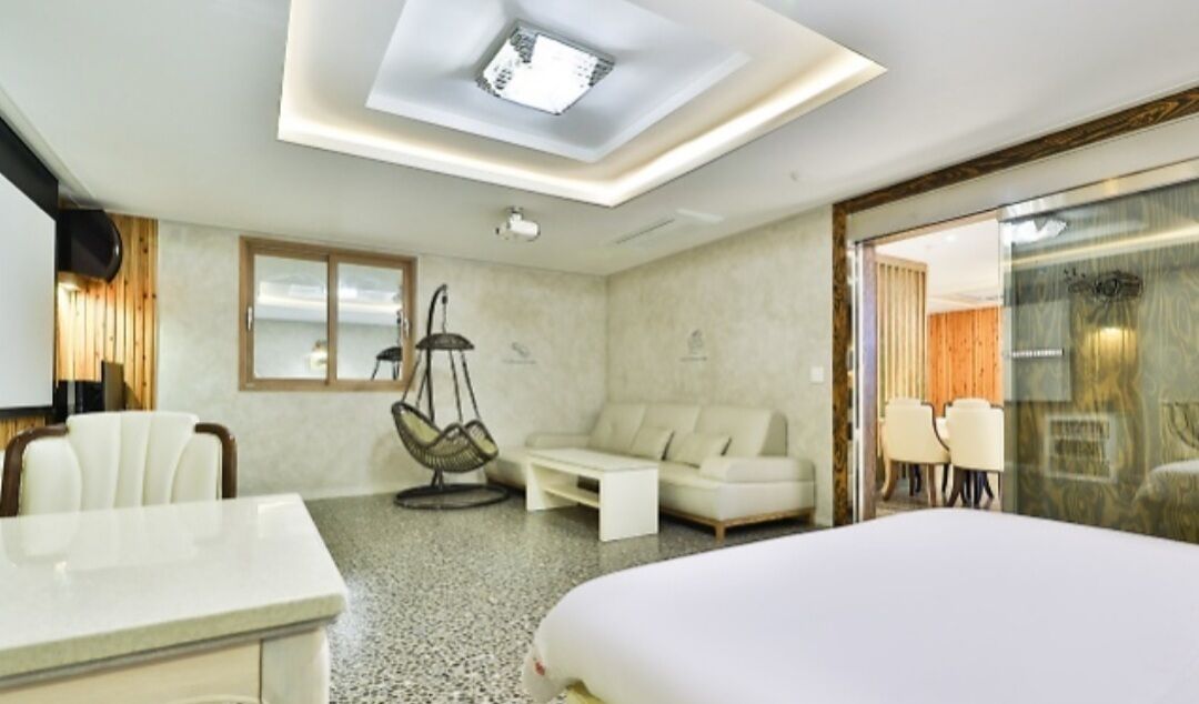 A modern hotel room with a skylight, a sofa, a dining table, and a bed.