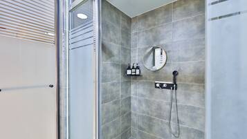 A modern shower area with a glass door, a handheld showerhead, and a wall-mounted mirror.