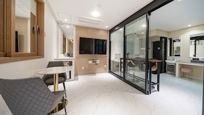 A modern kitchen with a dining area, large windows, and a flat-screen TV.