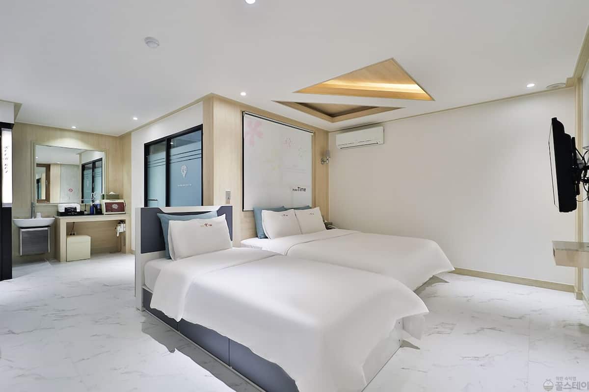 A modern hotel room with a bed, bedside table, and a mirror.