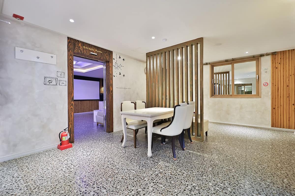 A dining area with a white table and chairs, a wooden partition, and a fire extinguisher on the floor.