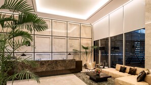 A modern reception area with a marble reception desk, a leather sofa, and a large window with blinds.
