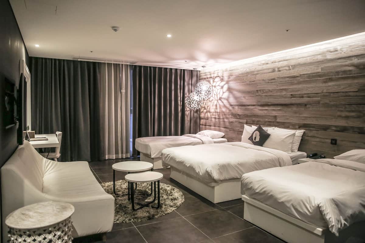 Un dormitorio moderno con una cama grande, un sofá y una mesita.