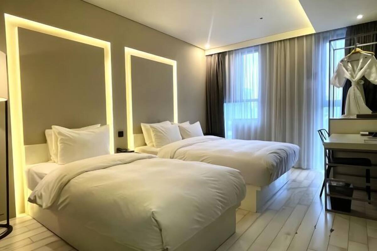 Una habitación de hotel con dos camas, un escritorio y un espejo.