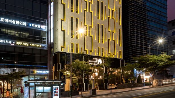 A modern hotel with a distinctive facade featuring a geometric pattern of windows and a prominent logo at the top.