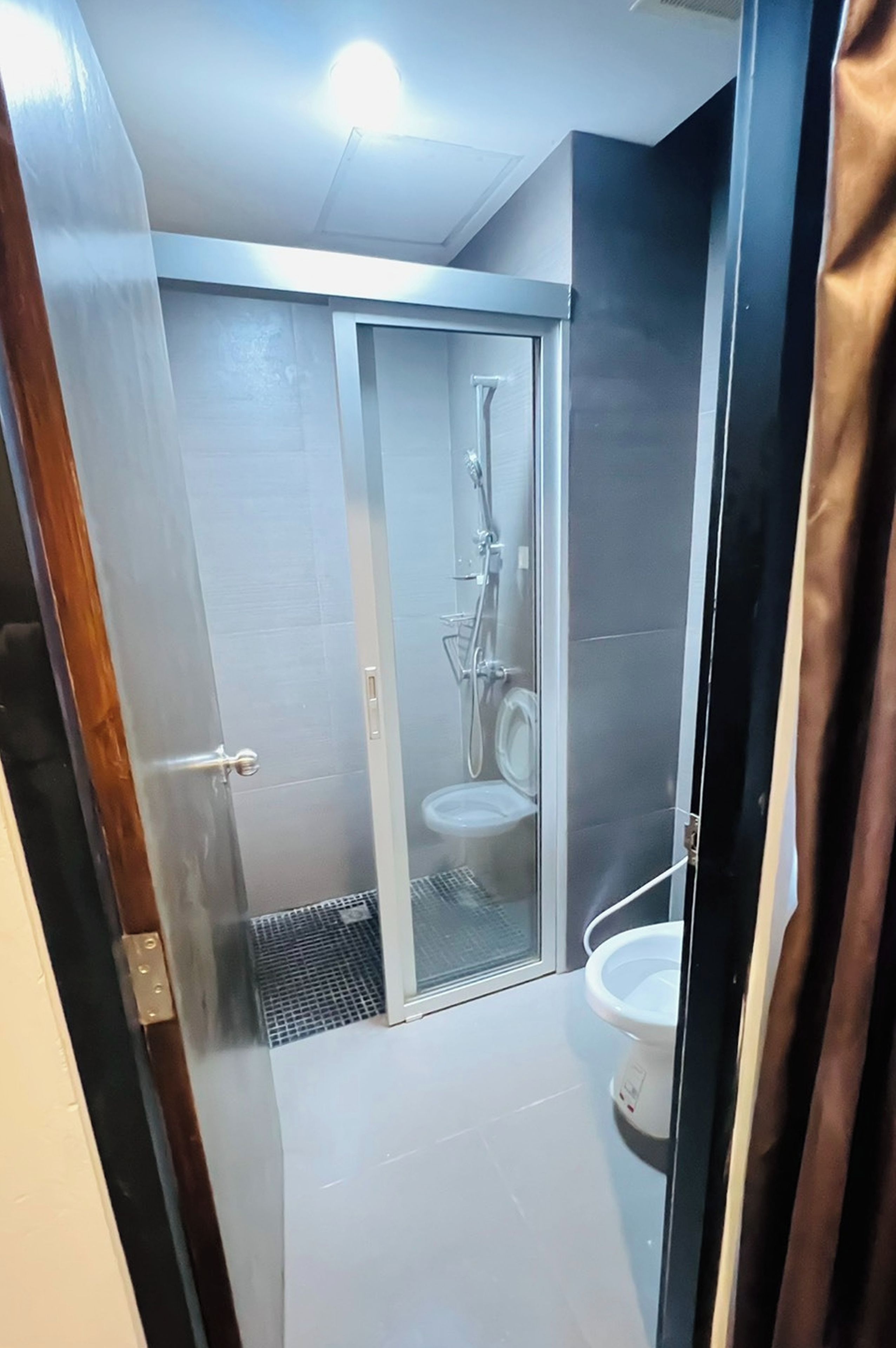 Un bagno moderno con cabina doccia in vetro, water e WC.