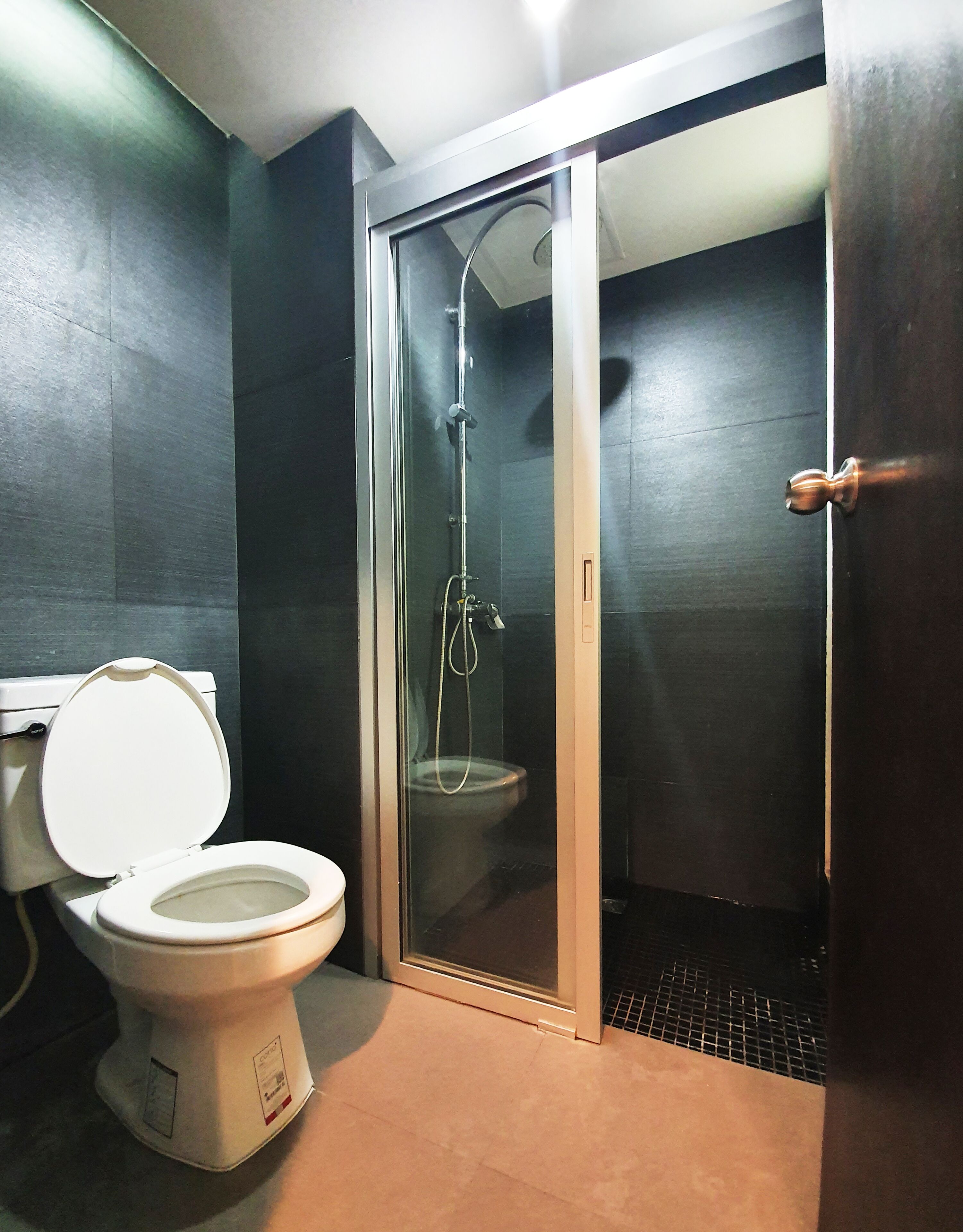 A bathroom with a toilet, a shower enclosure, and a door.