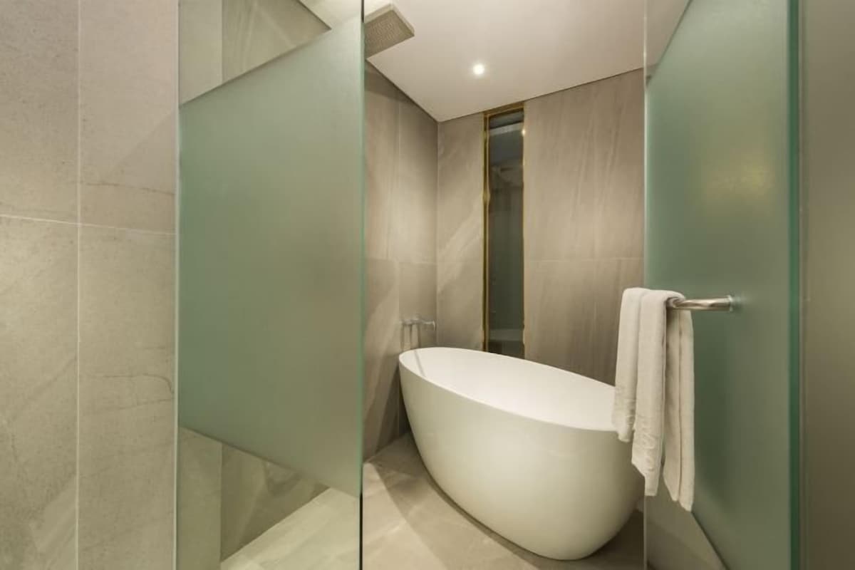 A modern bathroom with a freestanding bathtub, glass shower enclosure, and a towel rack.