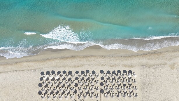 Vista aérea de una playa con una fila de sillas de tomar el sol hexagonales.