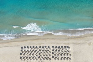 Vista aérea de una playa con una fila de sillas de tomar el sol hexagonales.