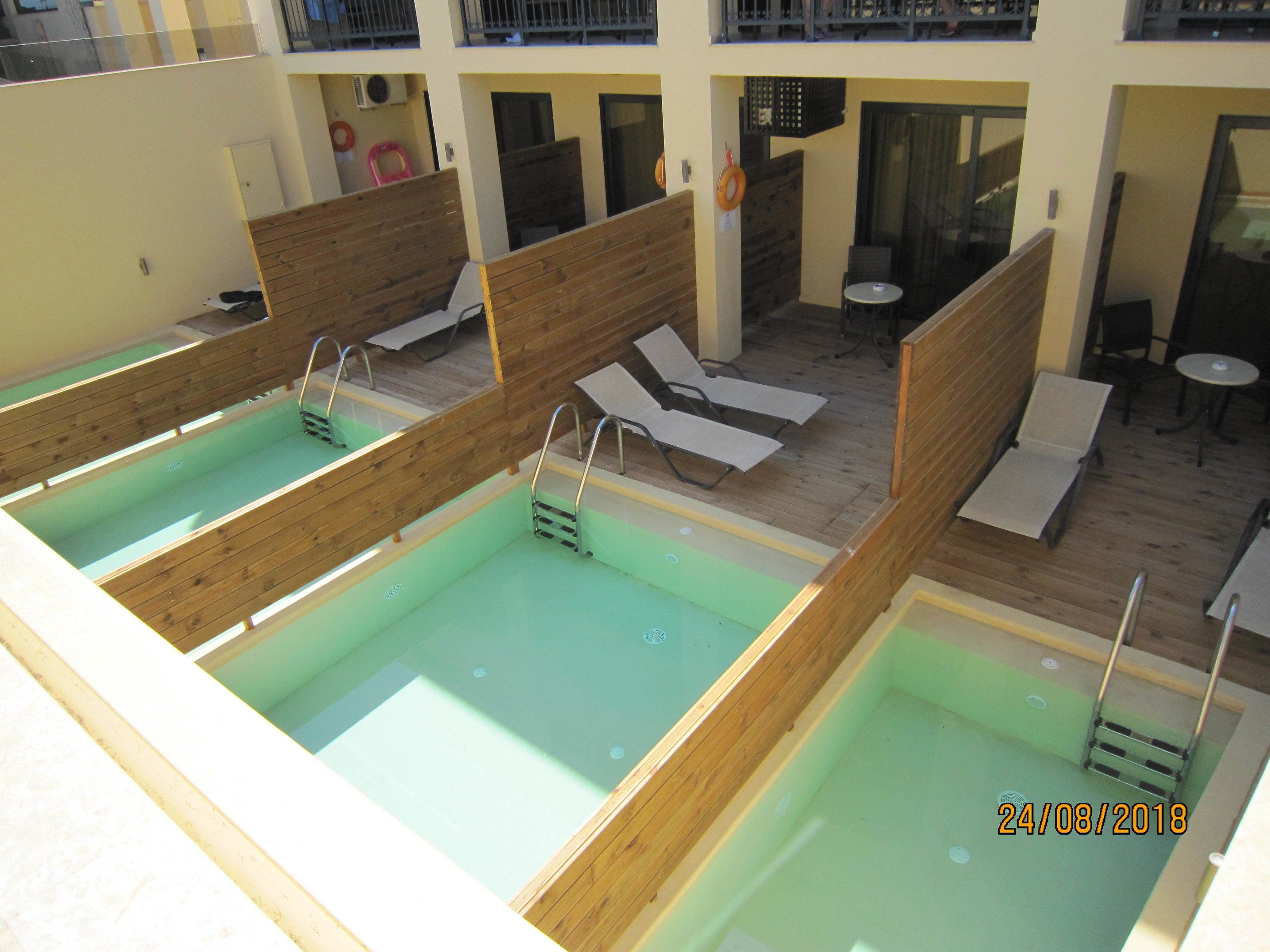 A rooftop pool area with multiple sun loungers and a small table.