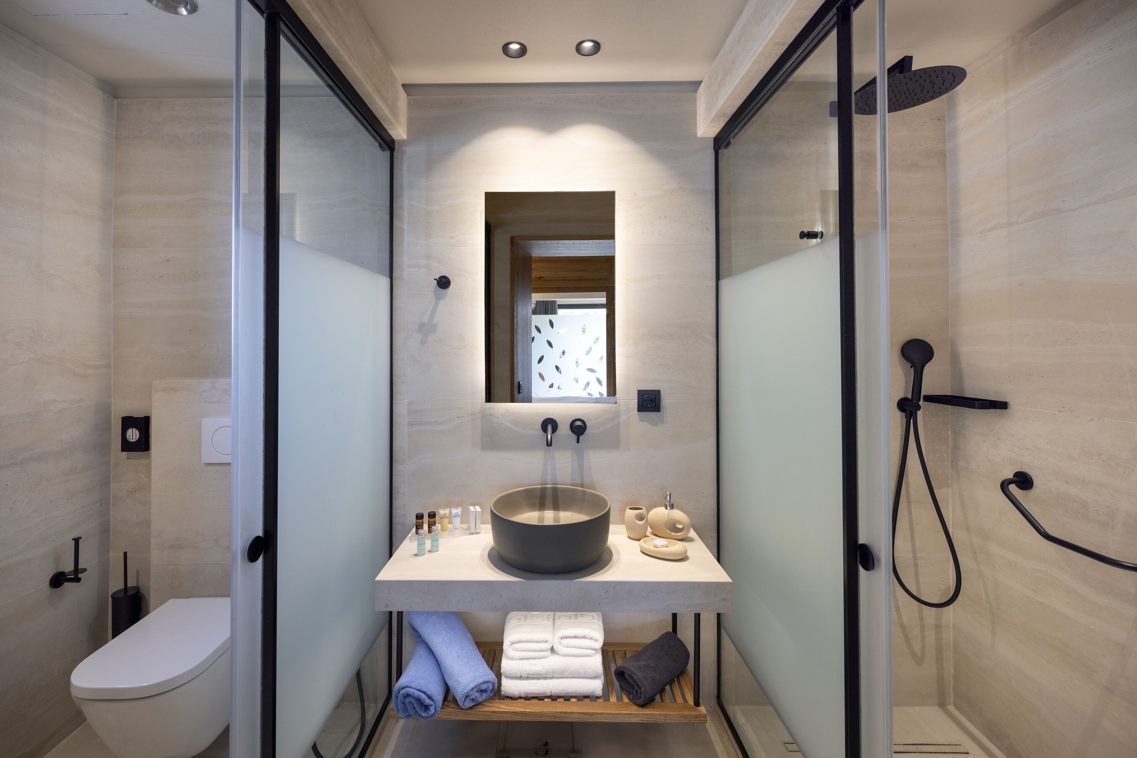 A modern bathroom with a glass-enclosed shower, a large round sink, and a mirror above the sink.