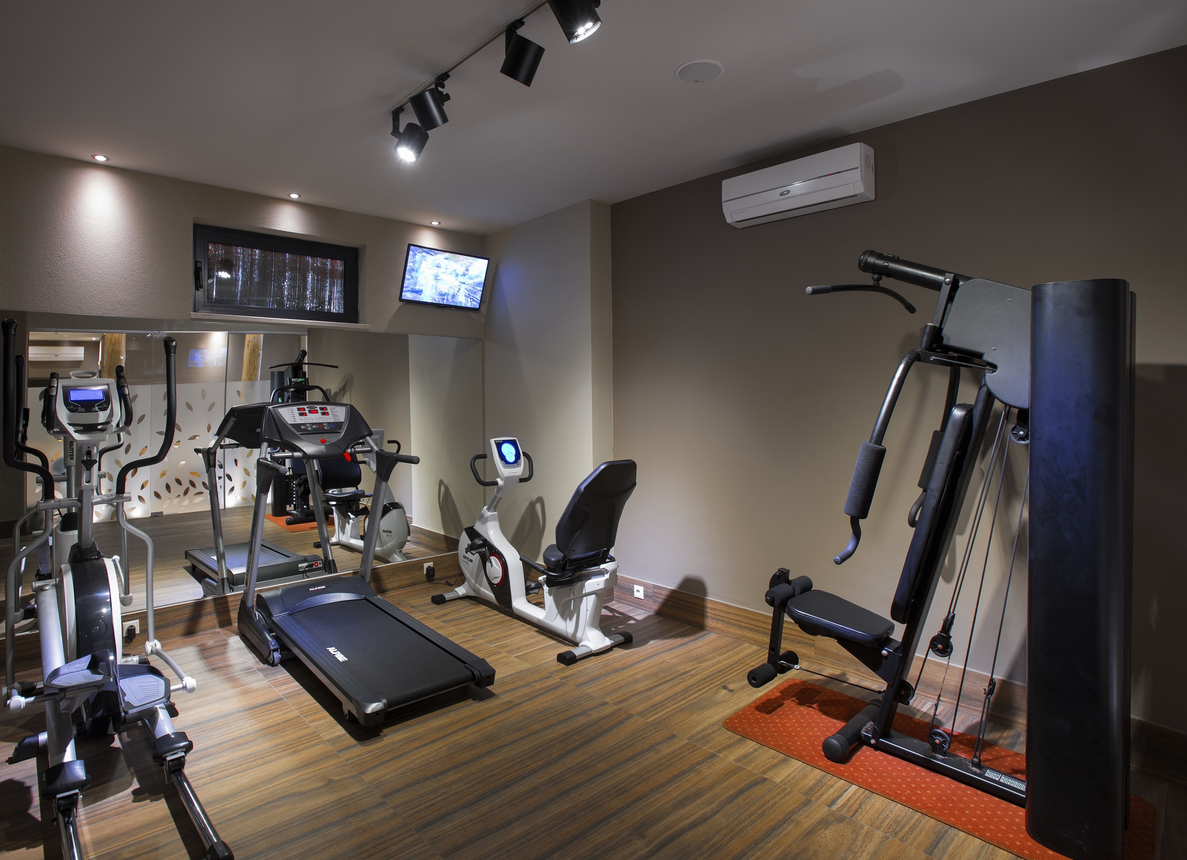 A gym with various exercise equipment including treadmills, elliptical machines, and a rowing machine.