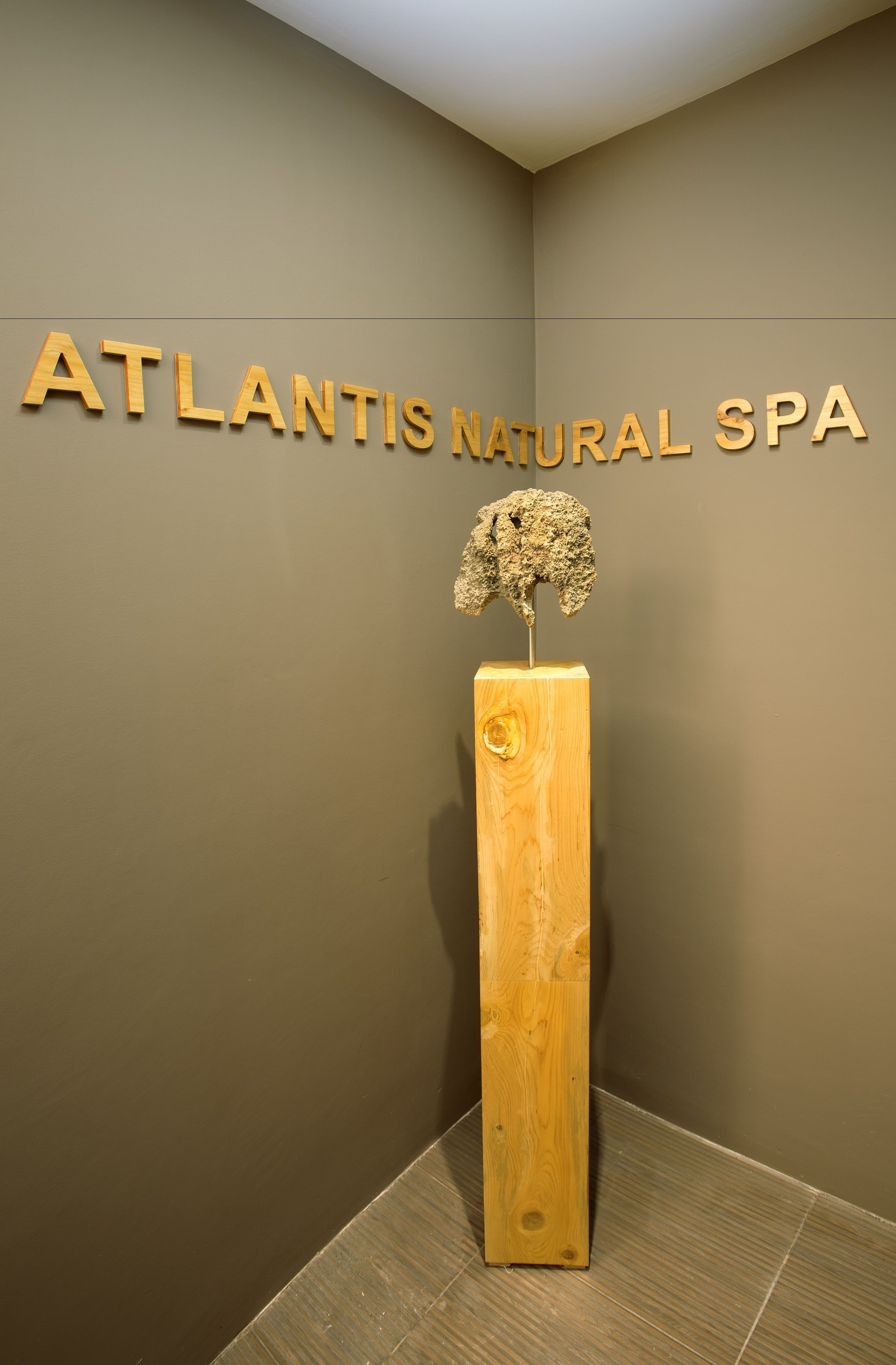 A sign for 'Atlantis Natural Spa' with a wooden sculpture of a tree on a pedestal.