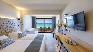 Habitación de hotel con una cama grande, un escritorio con una bandeja de comida, un televisor y un balcón con vista al mar.