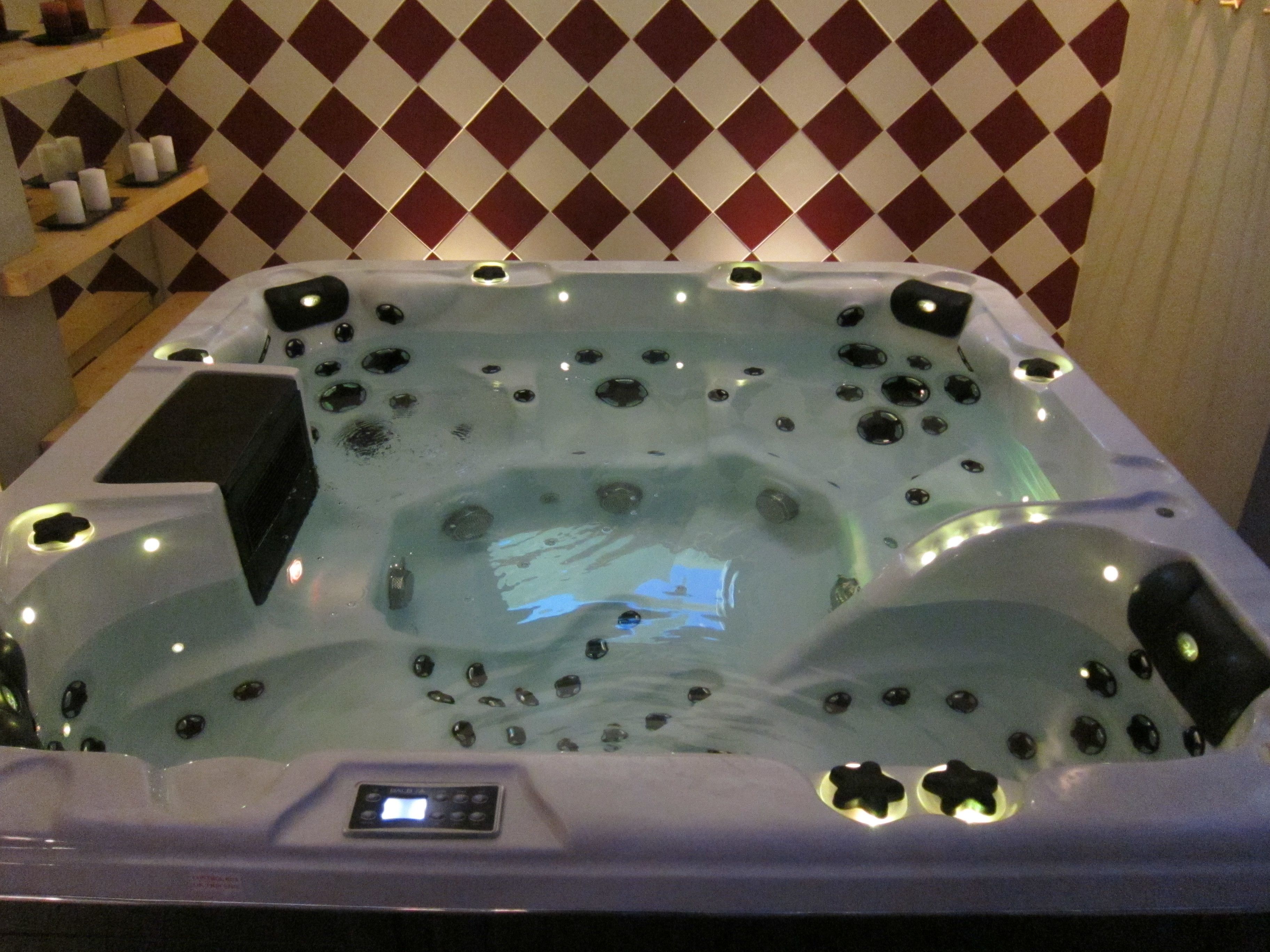 Uma banheira de hidromassagem com painel de controle, emoldurada por um padrão de parede xadrez.