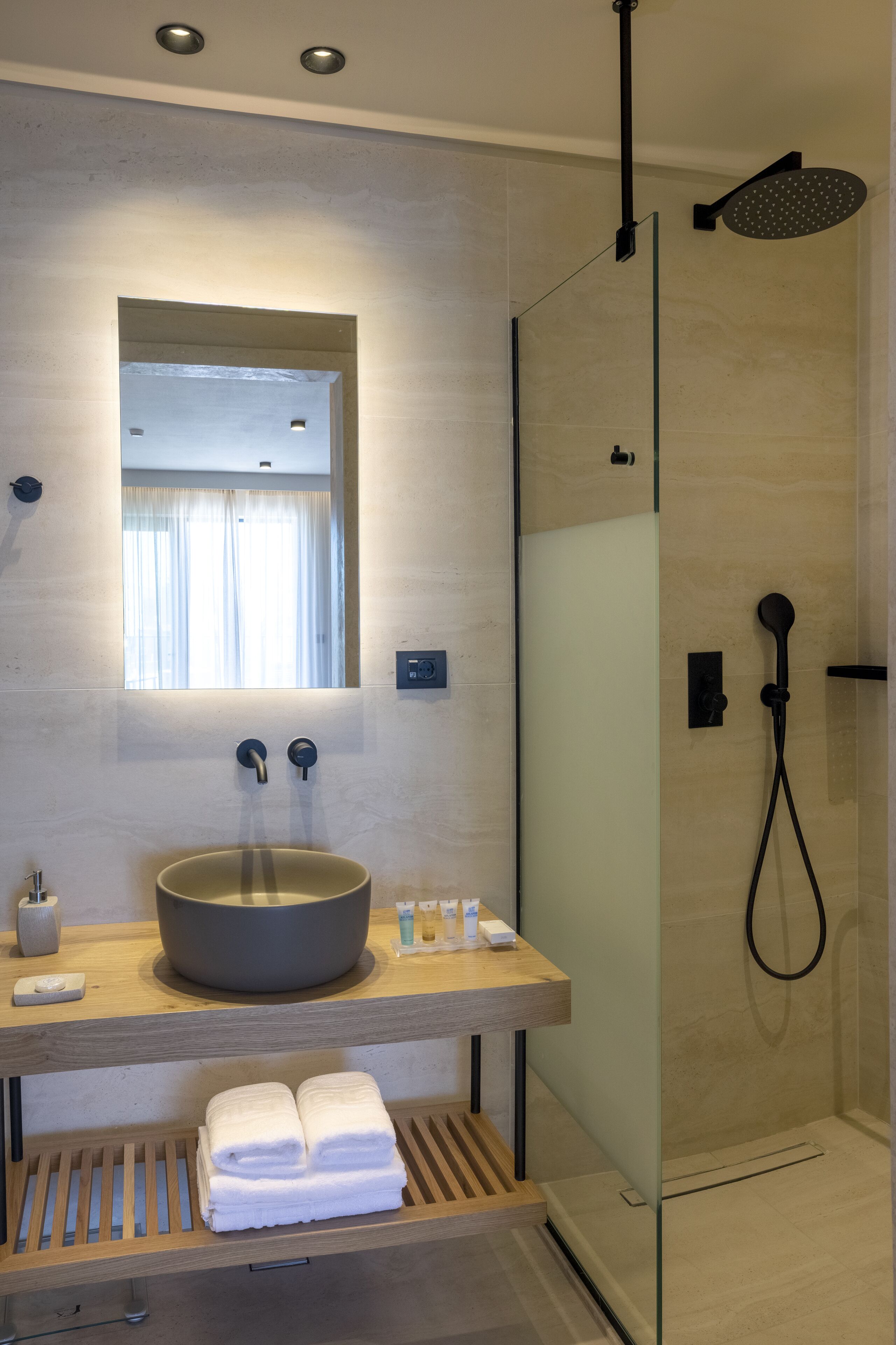 A modern bathroom with a large sink, mirror, and glass-enclosed shower.