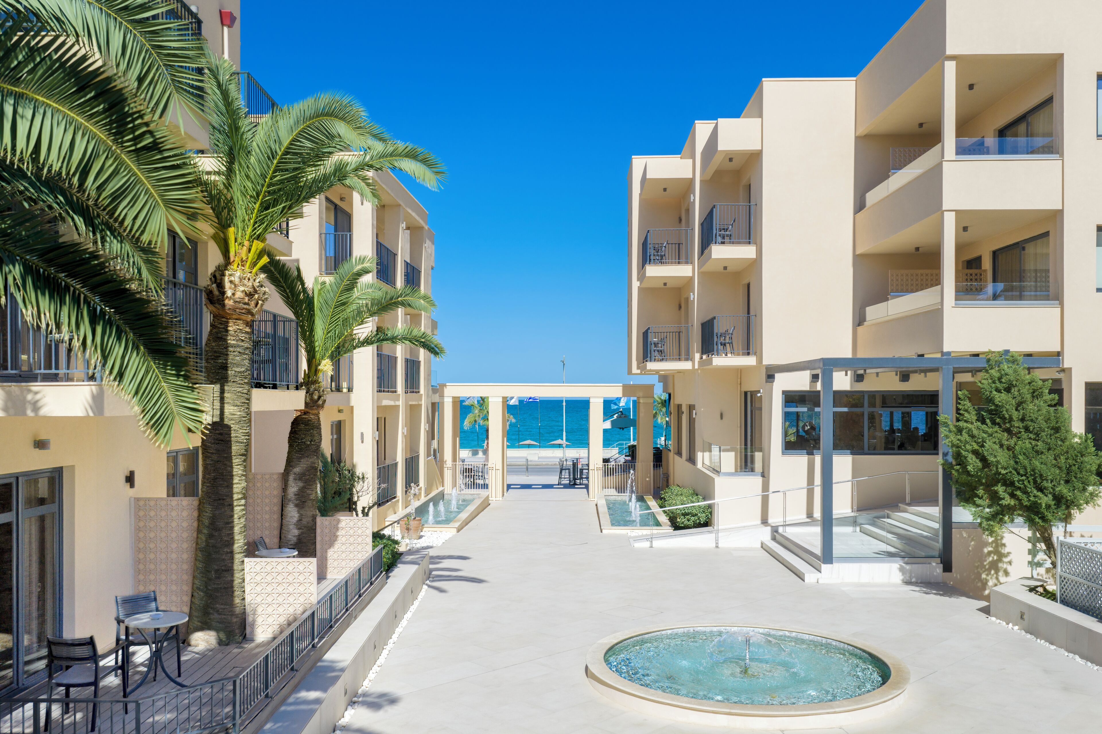 A resort with a pool, palm trees, and a view of the ocean.