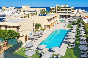 Una piscina al aire libre, sombrillas, sillones reclinables de piscina