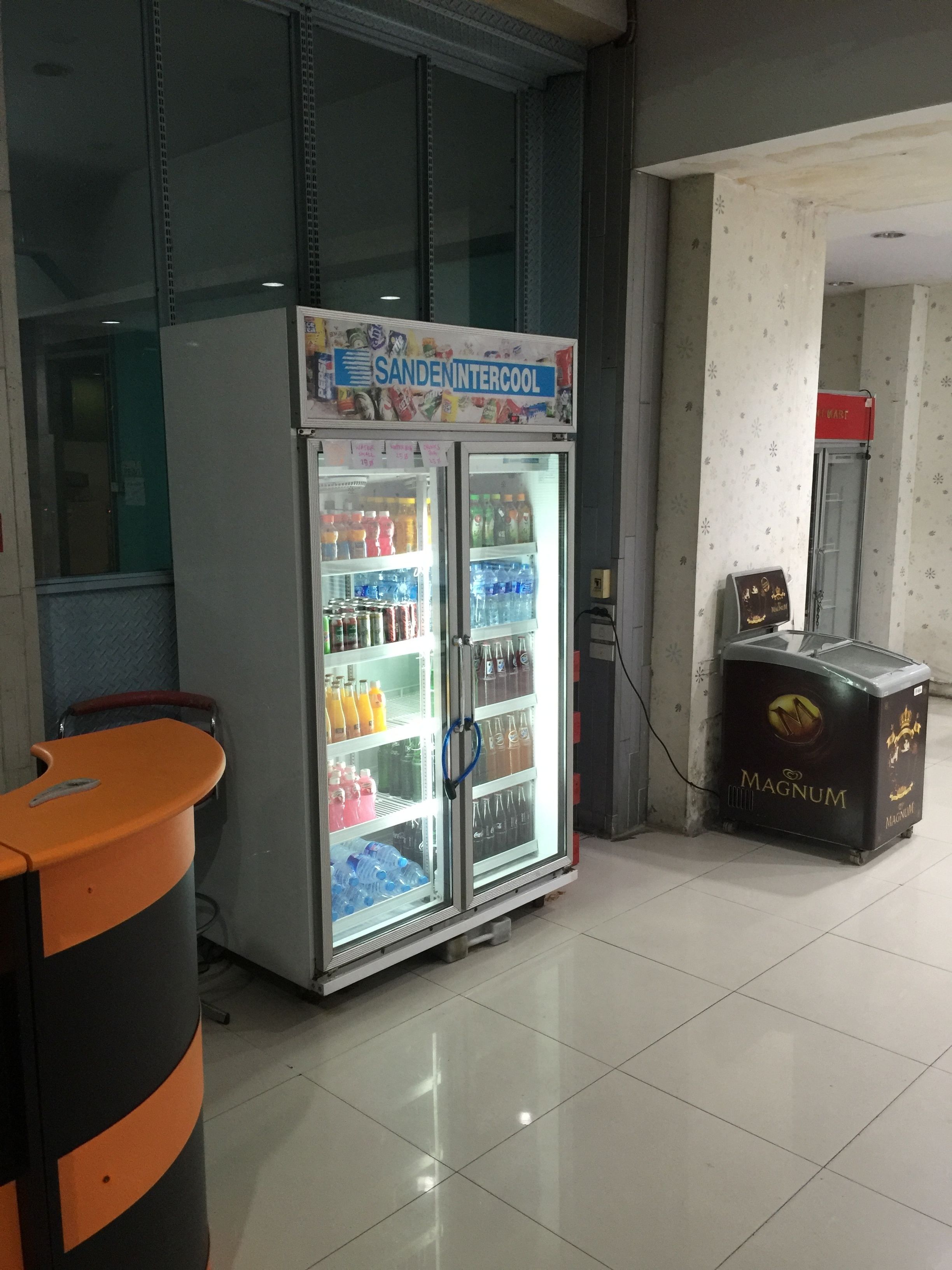 A vending machine with a variety of drinks and a refrigerator with a 'SANDEN INTERCOOL' sign.