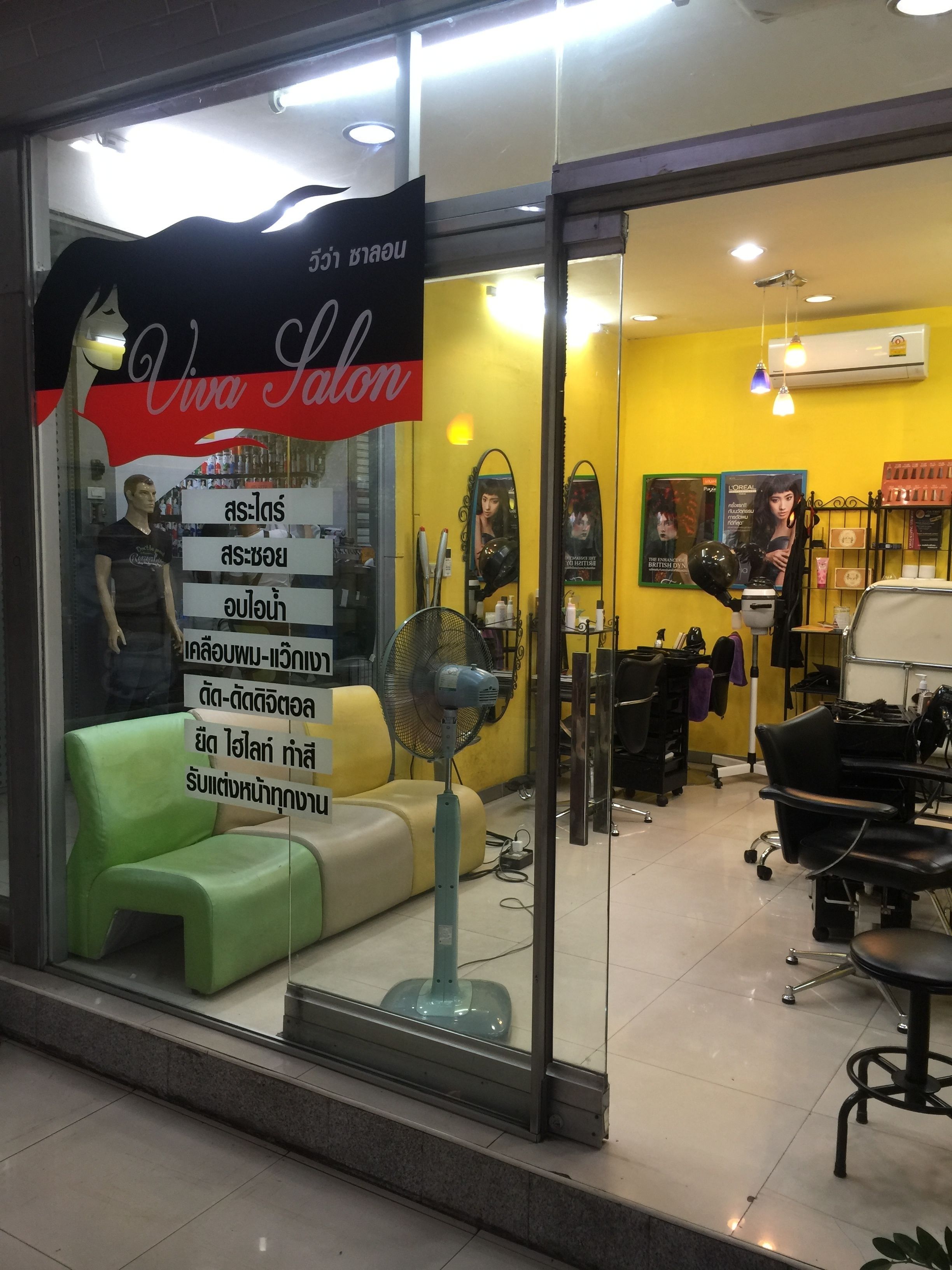 A salon with a green chair, a fan, and a mirror.
