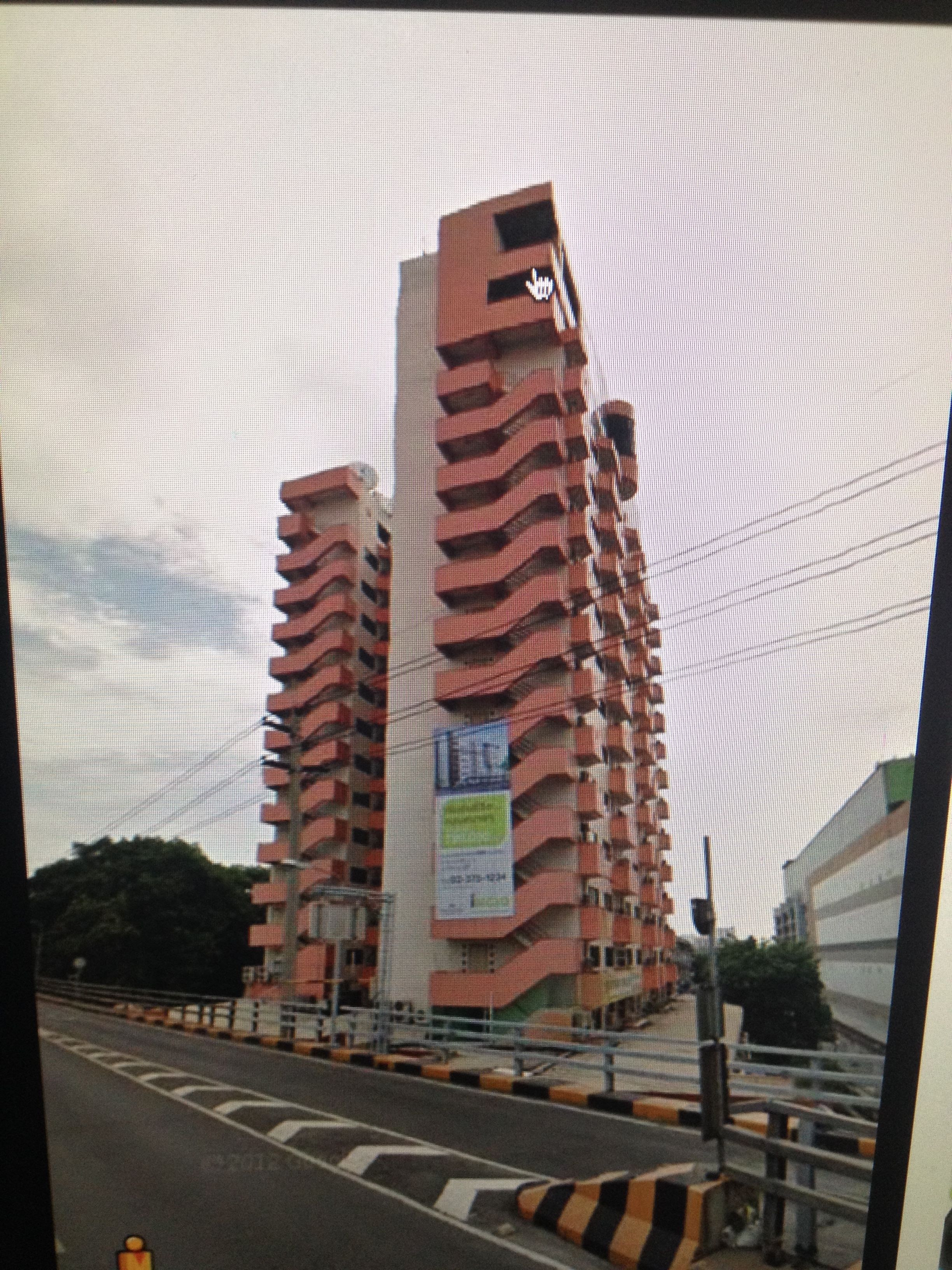 A high-rise building with a distinctive red and white facade, featuring a prominent 'H' logo on the top.