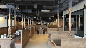 A modern restaurant interior with booth seating, high ceilings, and exposed ductwork. - Mall Suites Hotel (Bangkok)