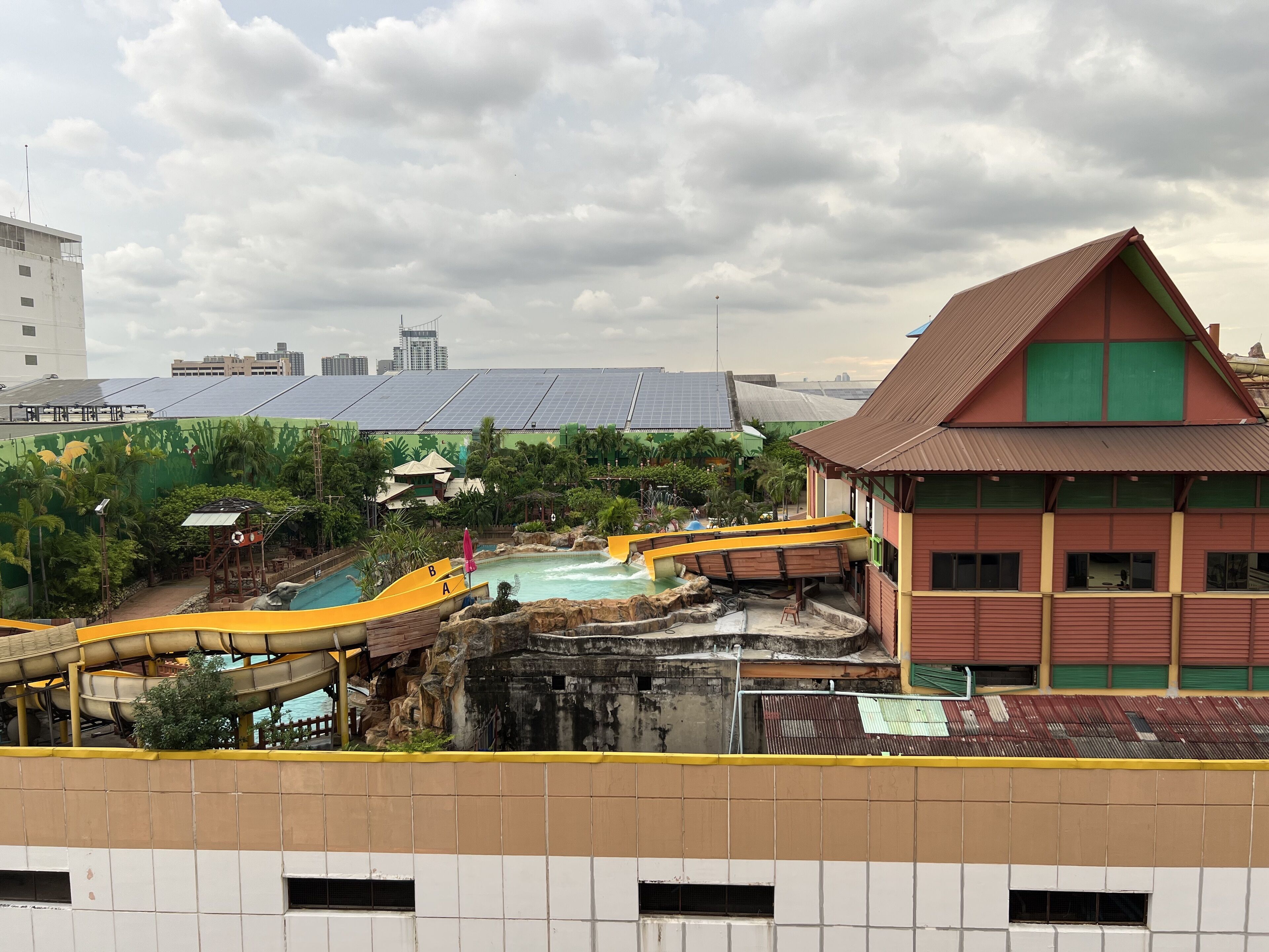 A water park with a slide, a pool, and a building with a red roof.