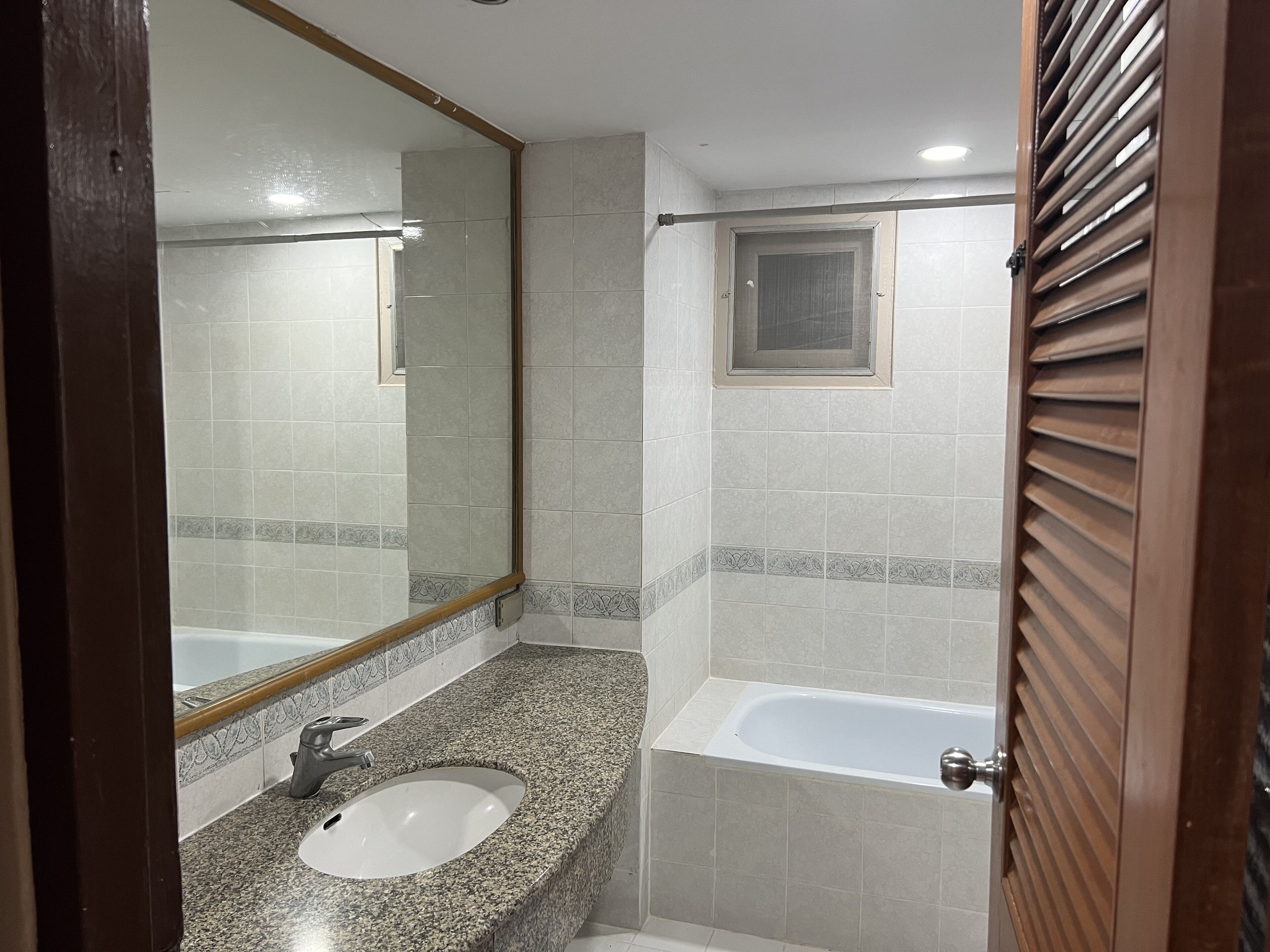 A bathroom with a sink, mirror, and bathtub.