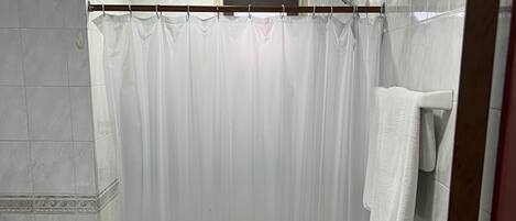 A bathroom with a toilet, a shower curtain, and a towel rack.