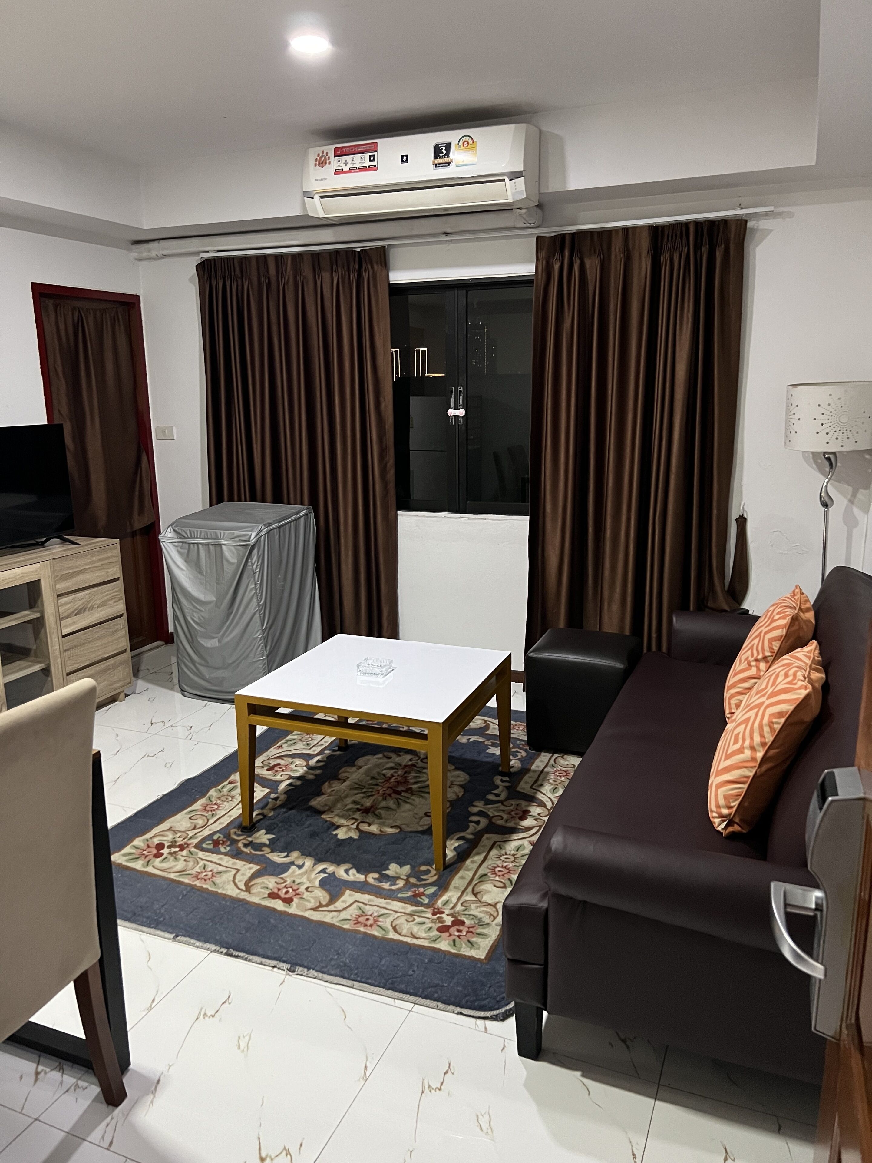 A living room with a sofa, a coffee table, a TV, and a covered table.