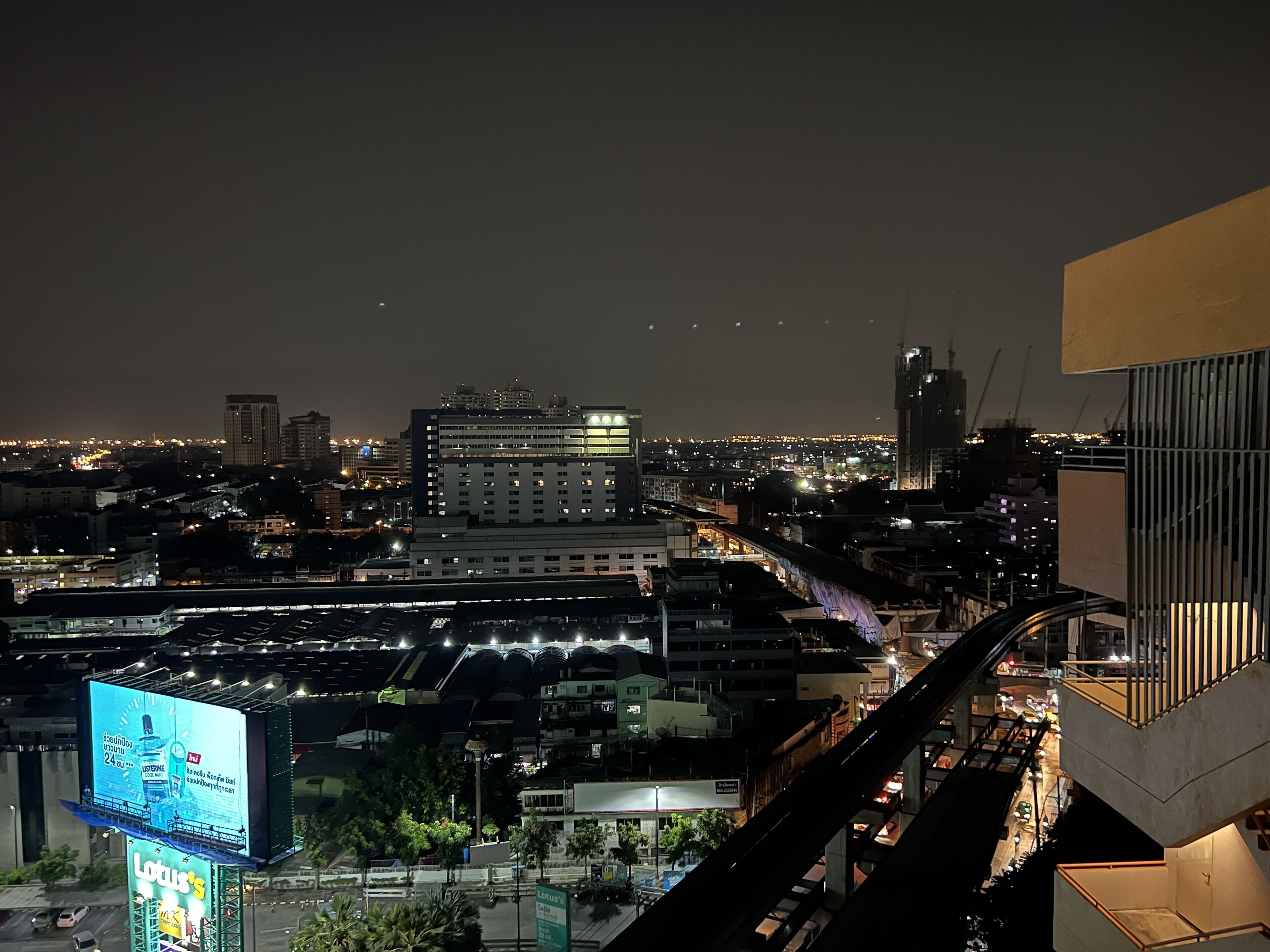 A nighttime cityscape with illuminated buildings and a prominent billboard advertising a hotel.