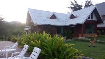 A building with a corrugated metal roof and a small giraffe statue in the front yard.