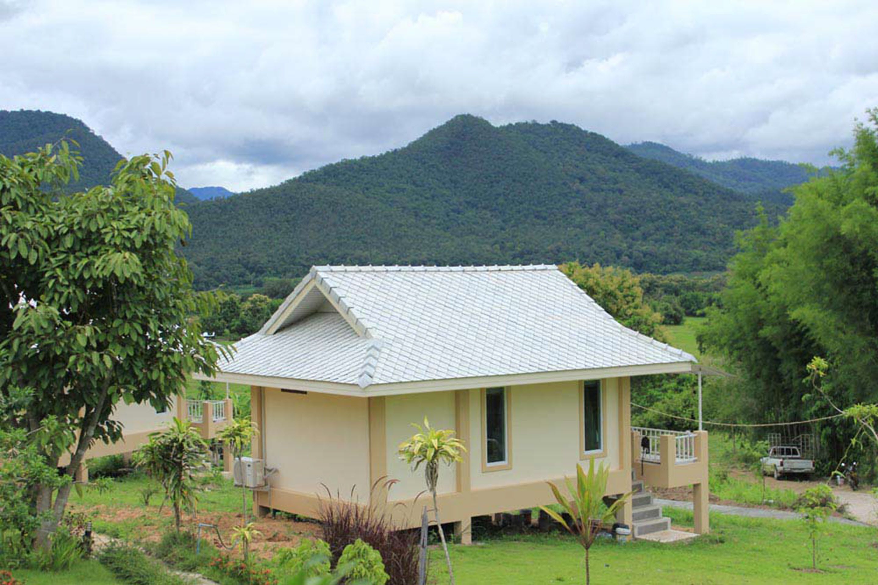 A single-story building with a sloped roof, surrounded by lush greenery and mountains in the background.