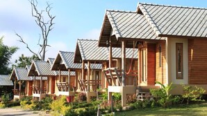 A row of wooden cabins with pitched roofs, each with a porch and outdoor seating. - Pai Iyara Resort (Pai)