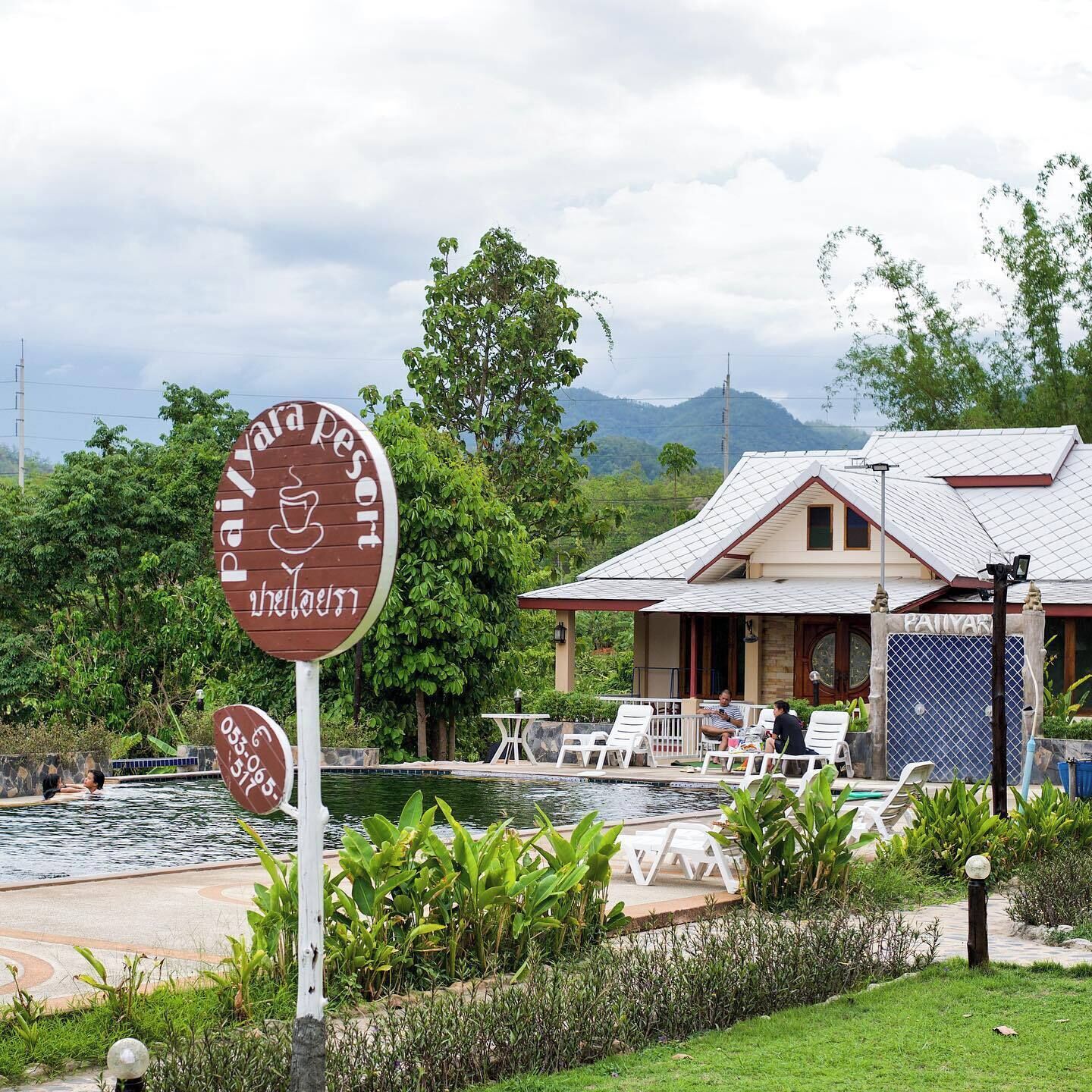 A resort with a swimming pool, lounge chairs, and a sign indicating a restaurant.