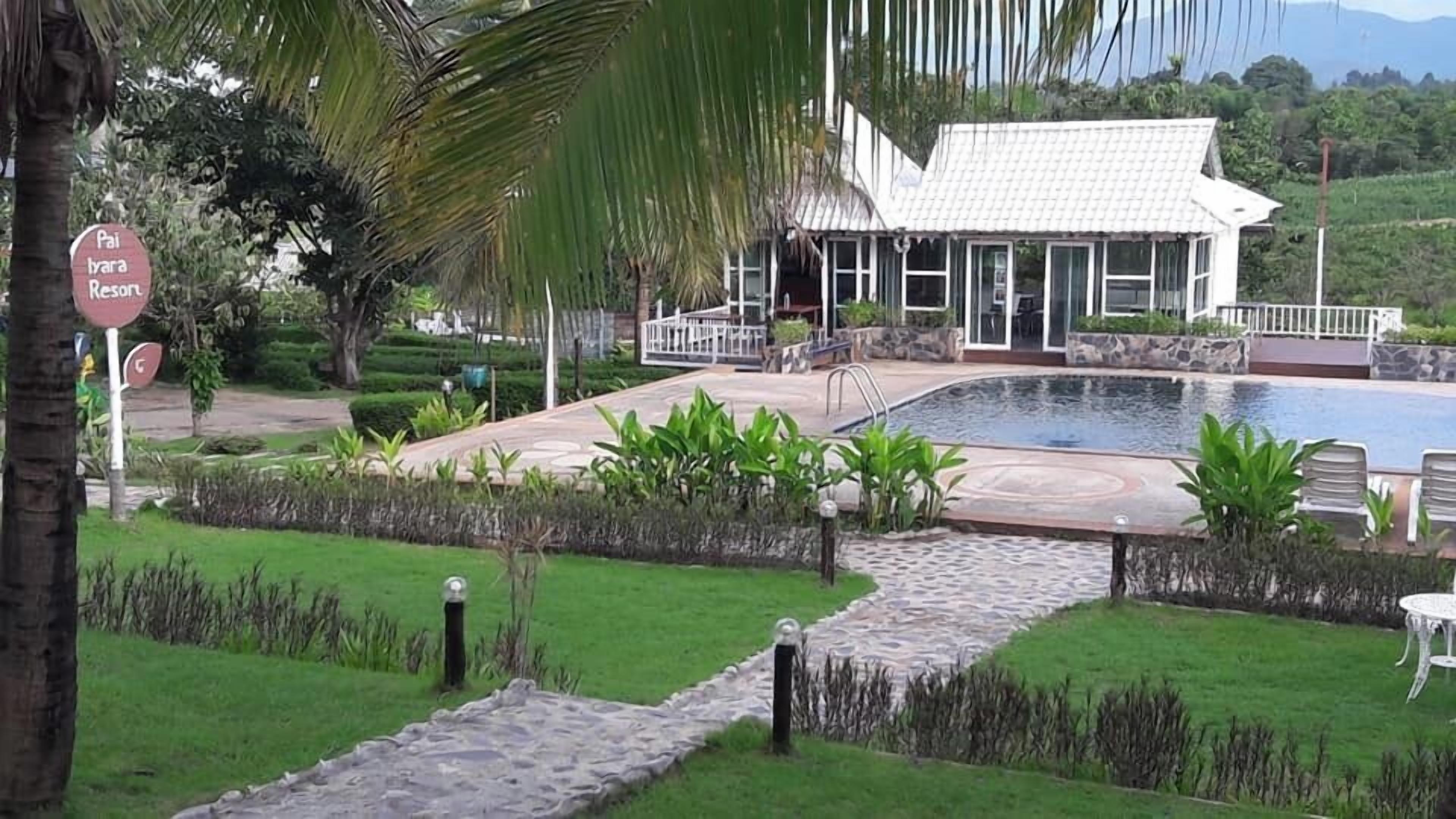 A resort with a swimming pool, a covered outdoor area, and a sign indicating a parking area.