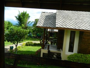 A house with a tiled roof, a porch, and a garden with trees and a pathway. - Pai Iyara Resort (Pai)