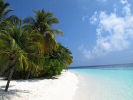Una playa cerca, arena blanca, sillas reclinables de playa, sombrillas