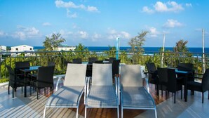 A deck with outdoor seating and a view of the ocean. - BEACH PALACE HOTEL (Hulhumalé)