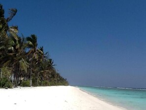 Una playa cerca, arena blanca, sillas reclinables de playa, sombrillas