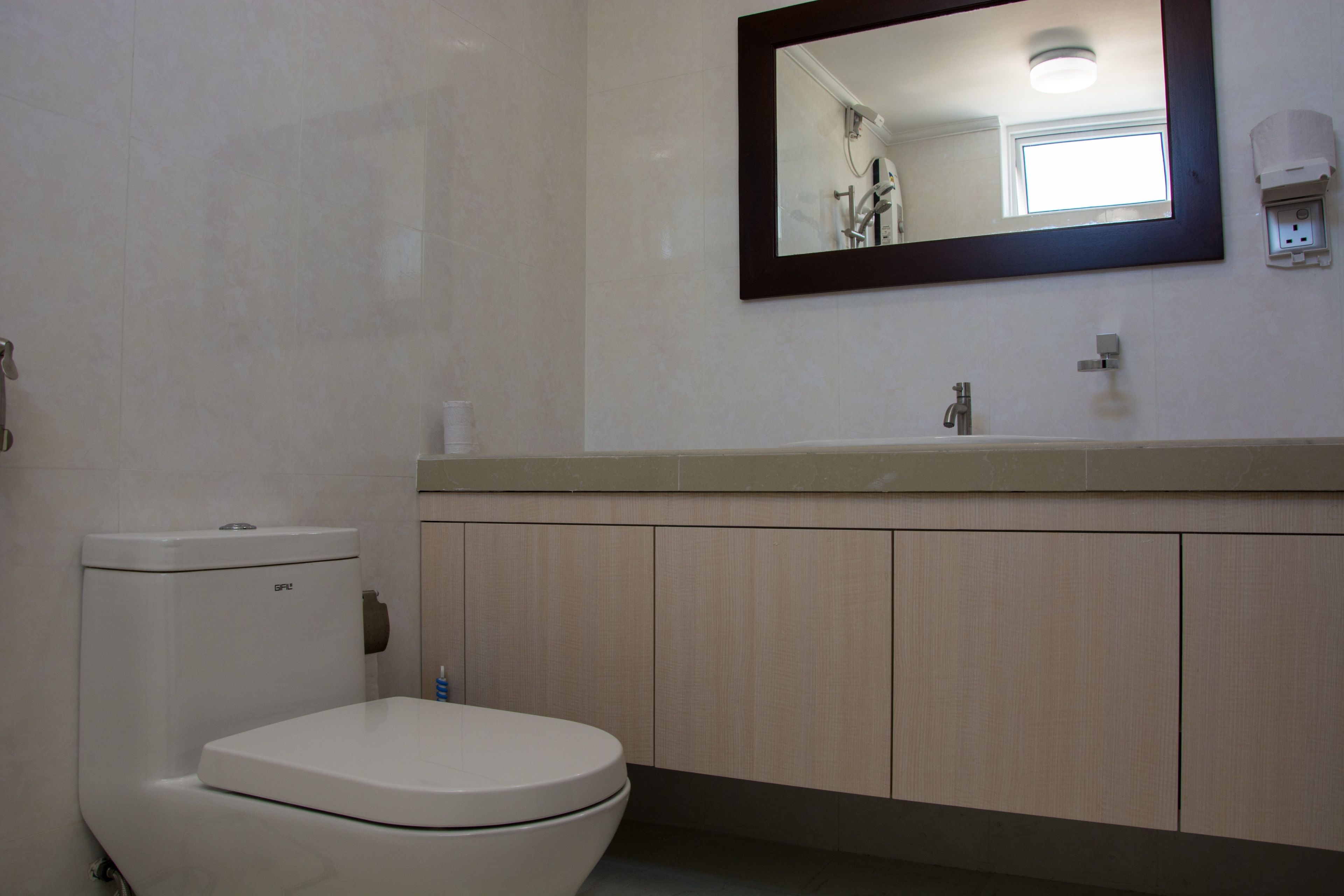Un baño con inodoro, lavabo, espejo y mueble.
