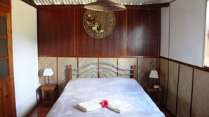 A room with a bed, two bedside tables, a hanging woven light fixture, and a decorative wall hanging. - Residence Foulsafat (Rodrigues Island)